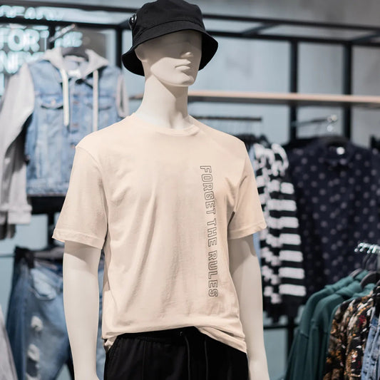 Mannequin wearing a beige t-shirt with text in a clothing store
