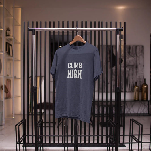 Blue t-shirt with 'CLIMB HIGH' text on a black metal rack.
