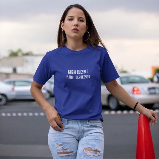 Woman wearing a blue t-shirt with text, standing in an outdoor setting with cars and a red cone.