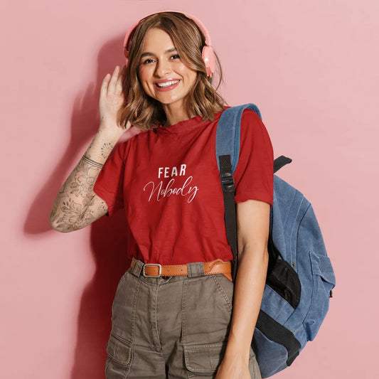 Woman wearing a red t-shirt with text, standing against a pink background
