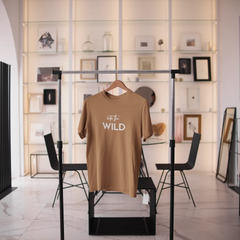 Brown t-shirt with 'Go Wild' text on a rack in a modern interior setting