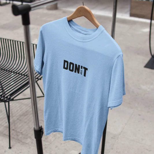 Light blue t-shirt with 'DON'T' text on a hanger against a blurred indoor background