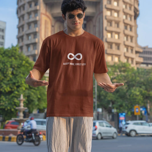 Person wearing a brown t-shirt with a logo in an urban setting