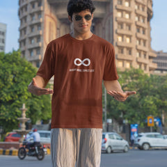 Person wearing a brown t-shirt with a logo in an urban setting