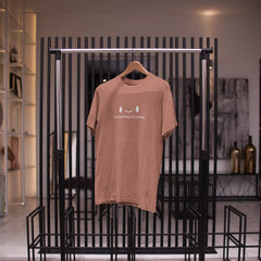 Brown t-shirt on a hanger against a black metal rack in a store setting