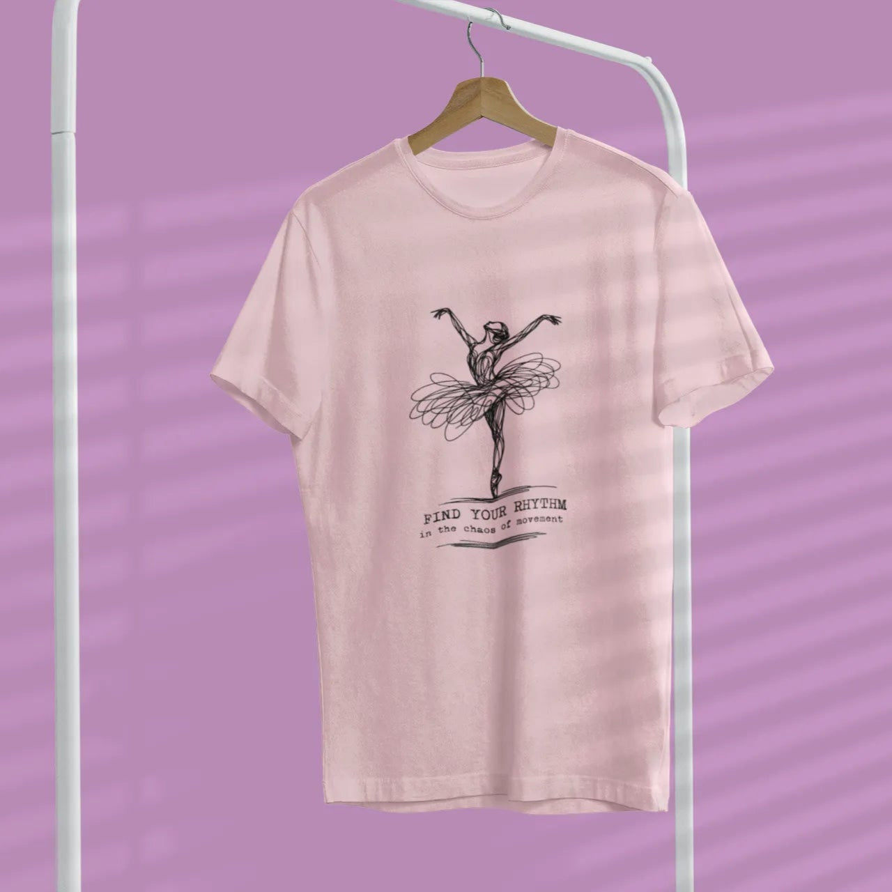 Pink t-shirt with a graphic design of a ballerina on a hanger against a purple background