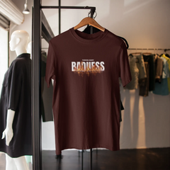 Brown t-shirt with 'Badness' text on a hanger in a clothing store.