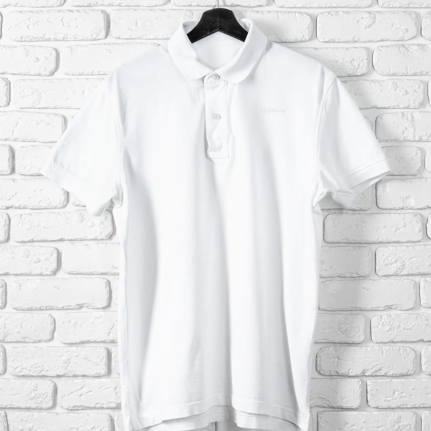 White blouse on a hanger against a white brick wall
