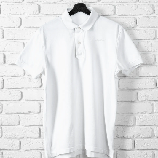 White blouse on a hanger against a white brick wall