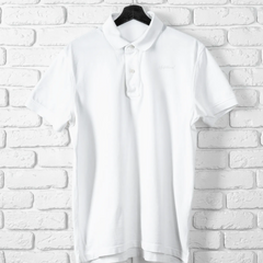 White blouse on a hanger against a white brick wall