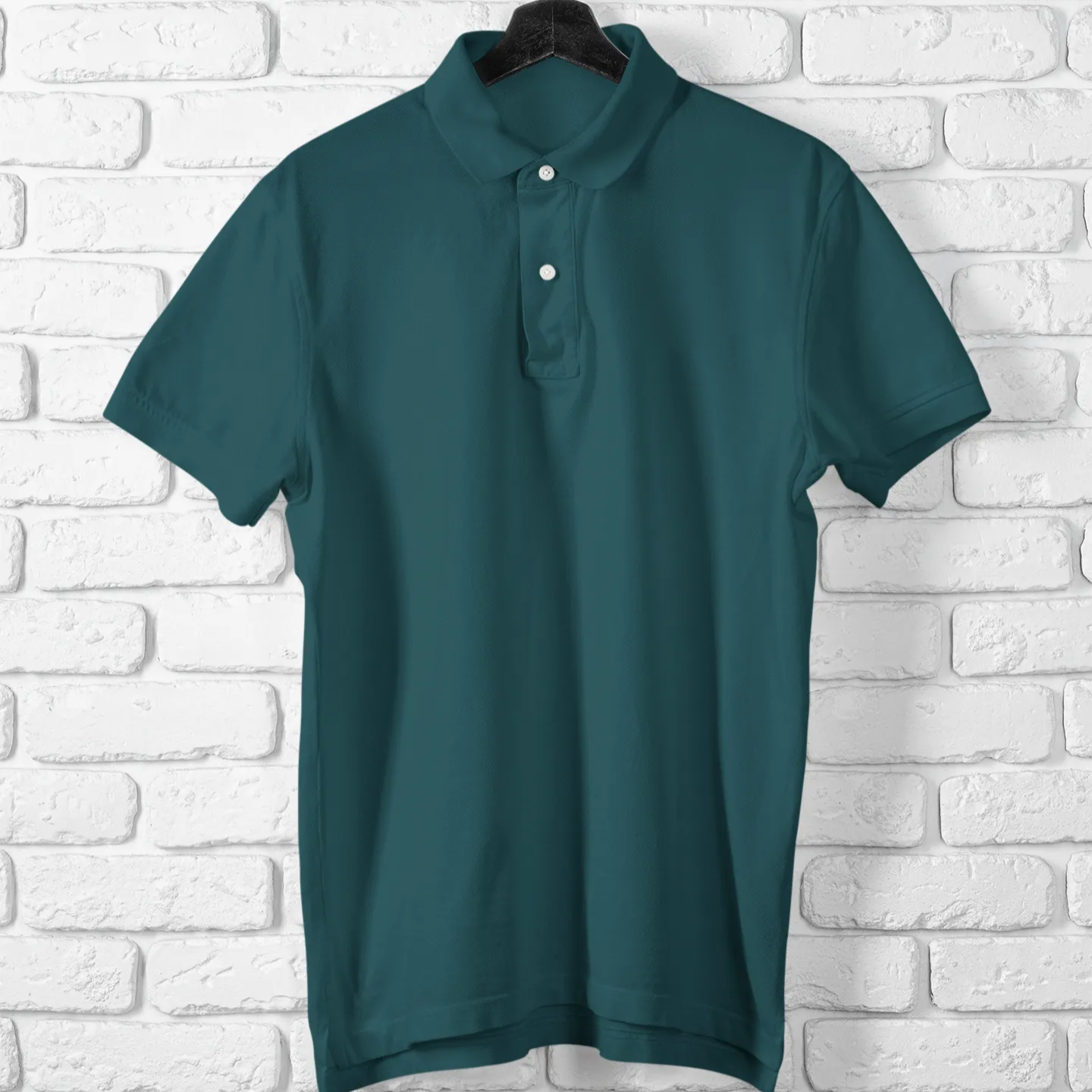 Green polo shirt on a hanger against a white brick wall