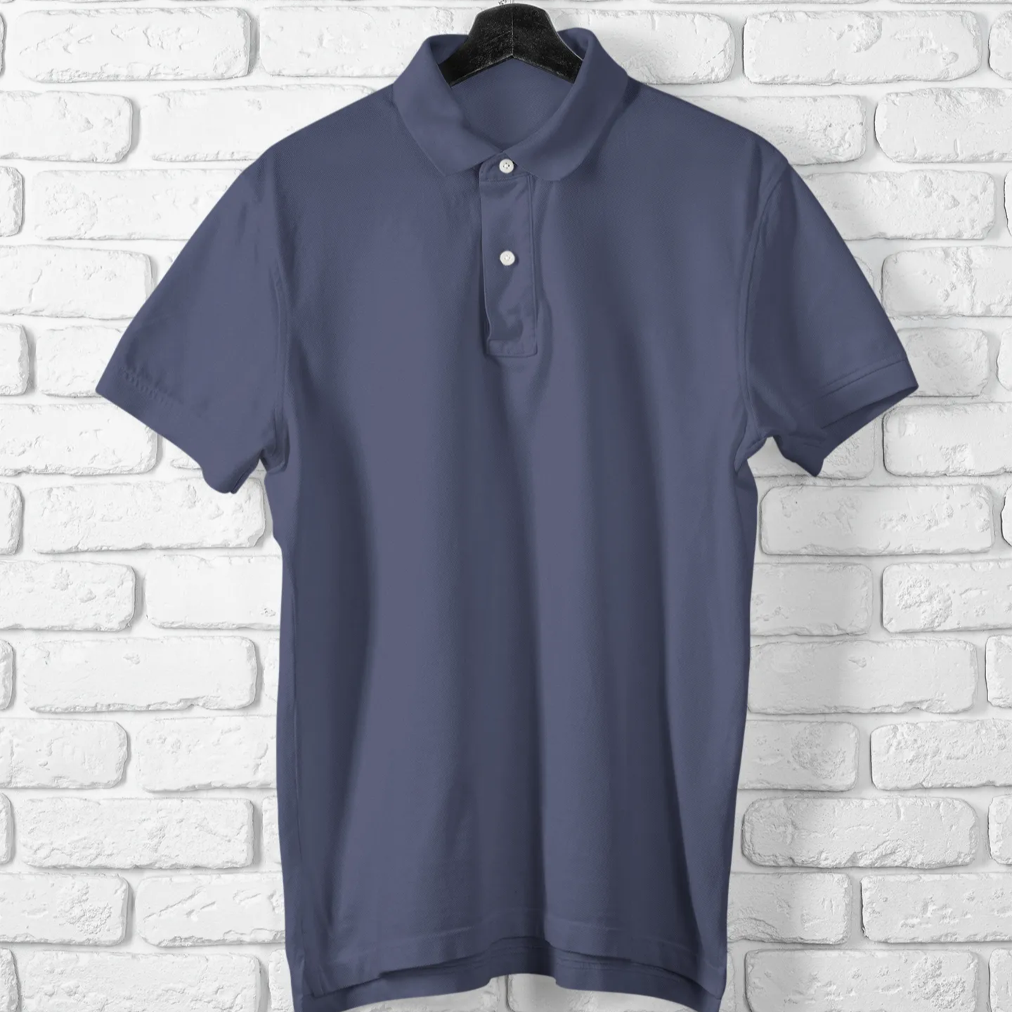 Blue polo shirt on a hanger against a white brick wall