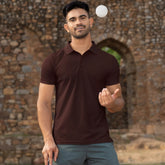 Man juggling a ball outdoors with a stone wall and grass in the background