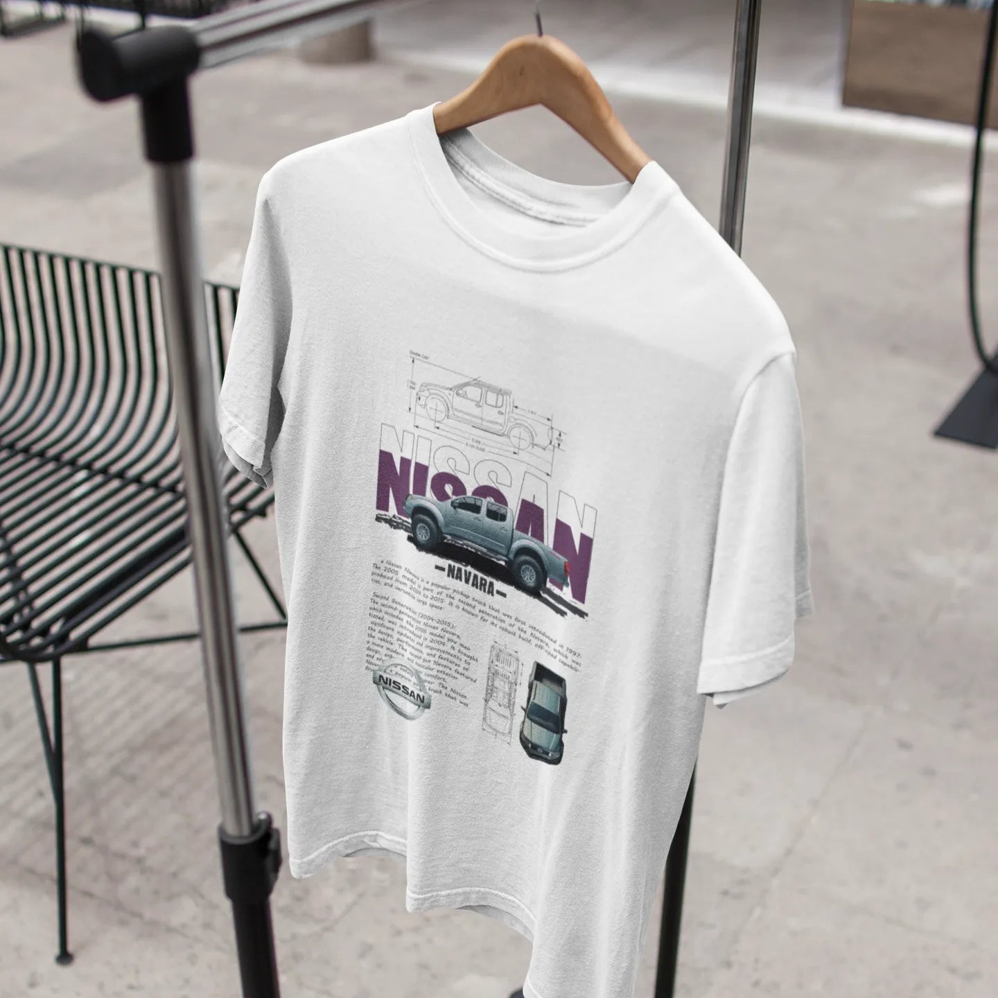 White t-shirt with Nissan graphic on a hanger against a blurred indoor background