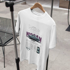 White t-shirt with Nissan graphic on a hanger against a blurred indoor background