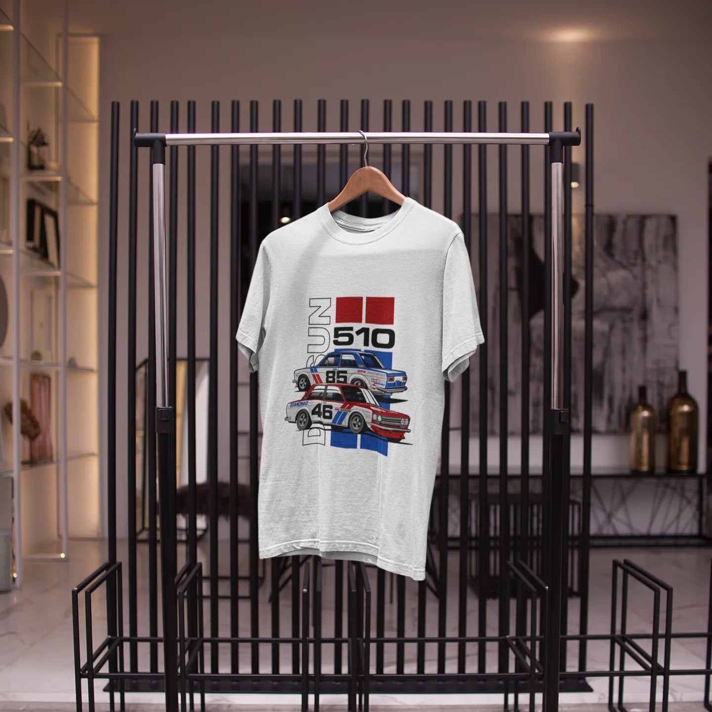 White t-shirt with graphic design on a black metal rack in a store setting