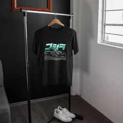 Black t-shirt with graphic design on a hanger in a room with a window.