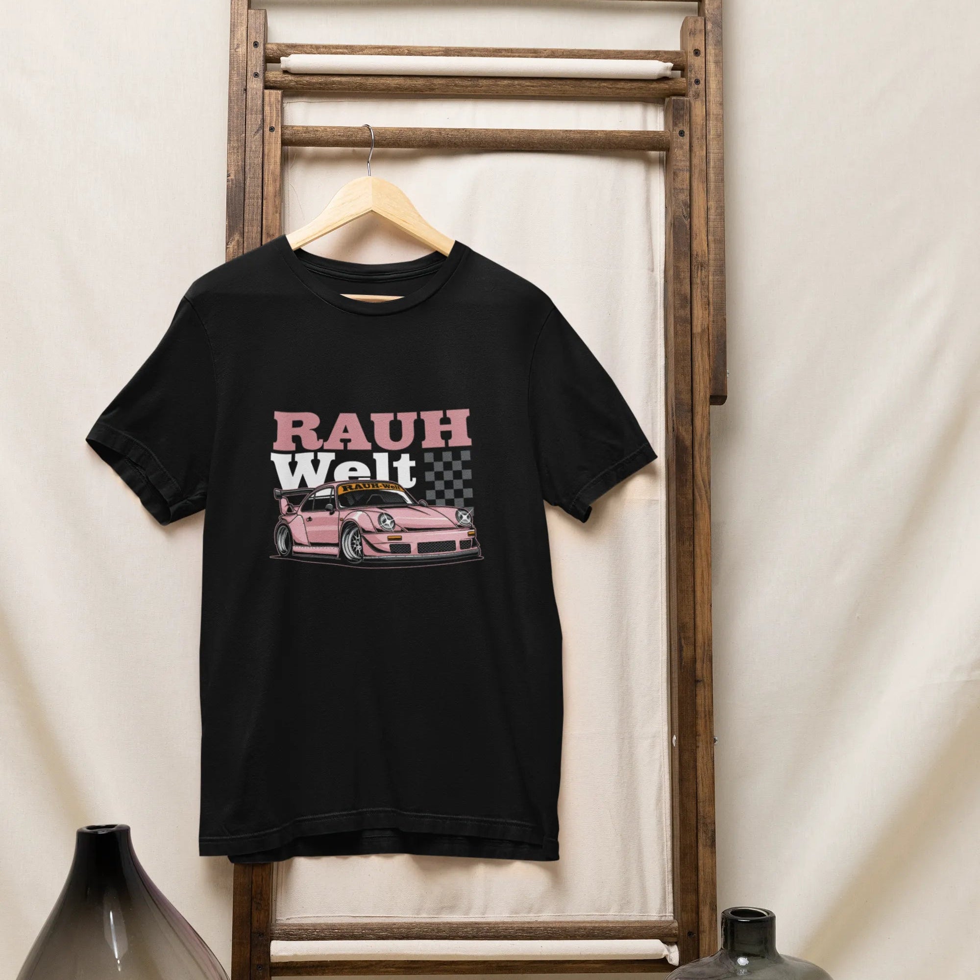 Black t-shirt with 'RAUH Welt' graphic on a wooden rack against a white wall.