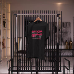 Black t-shirt with red graphic design on a hanger against a black metal rack.