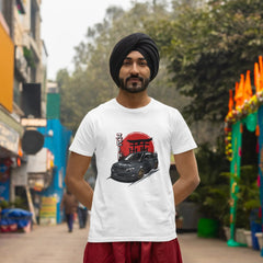 Man wearing a white t-shirt with a graphic design, standing on a street with colorful decorations.