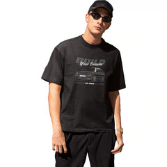 Two men in a casual setting, one using a phone and the other sitting at a table with a laptop.