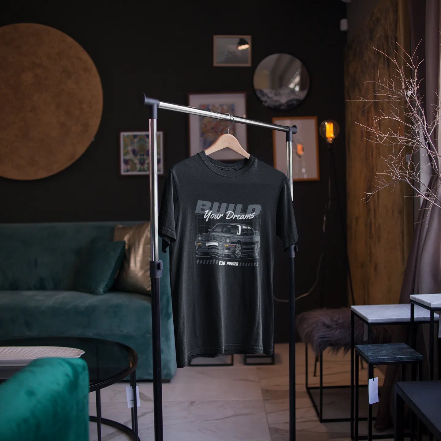 Black t-shirt with graphic design on a hanger in a room with dark walls and furniture.