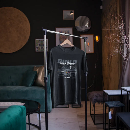 Black t-shirt with graphic design on a hanger in a room with dark walls and furniture.