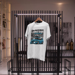White t-shirt with a graphic design on a black metal rack in a store setting.