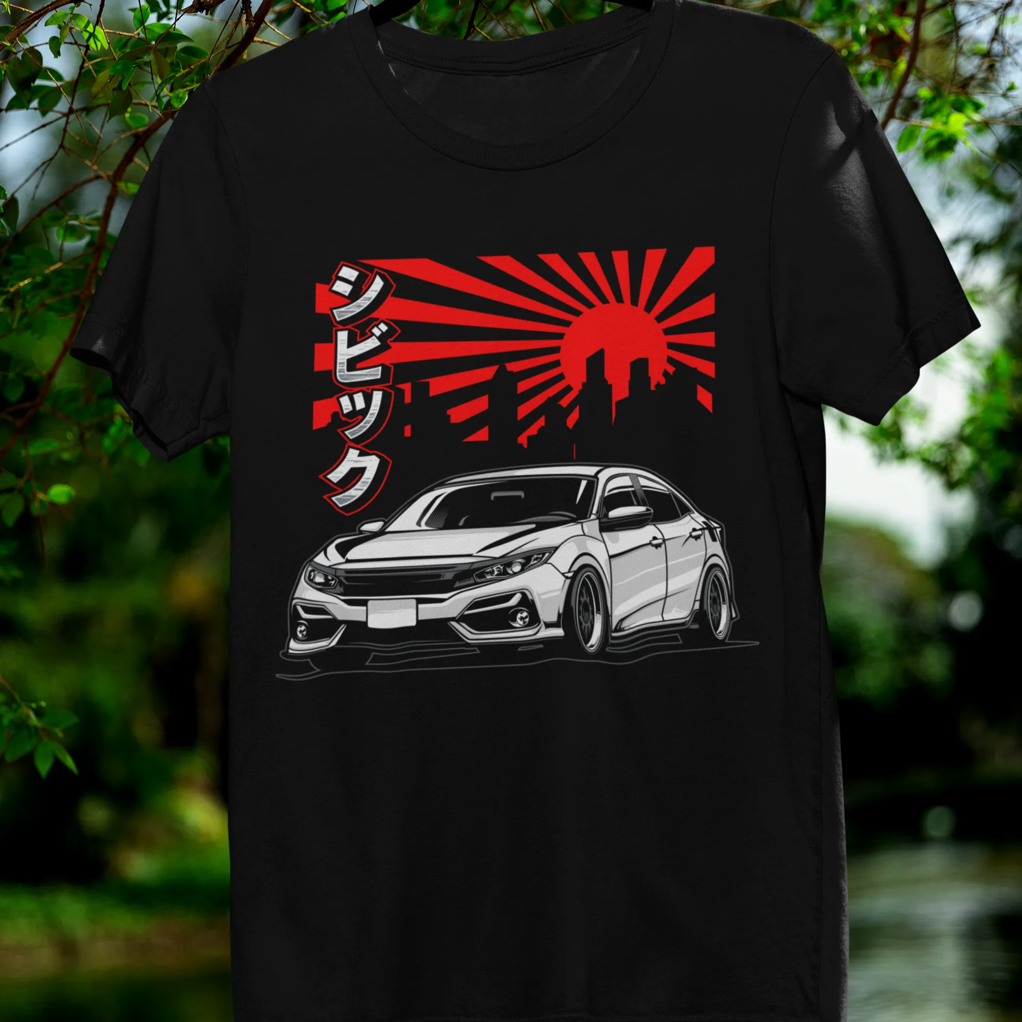 Black t-shirt with car graphic and red sun design on a hanger against a natural background