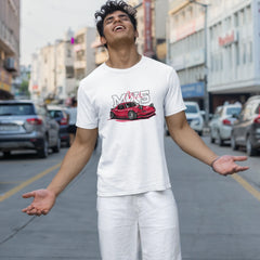 Man wearing a white t-shirt with a red car graphic on a city street