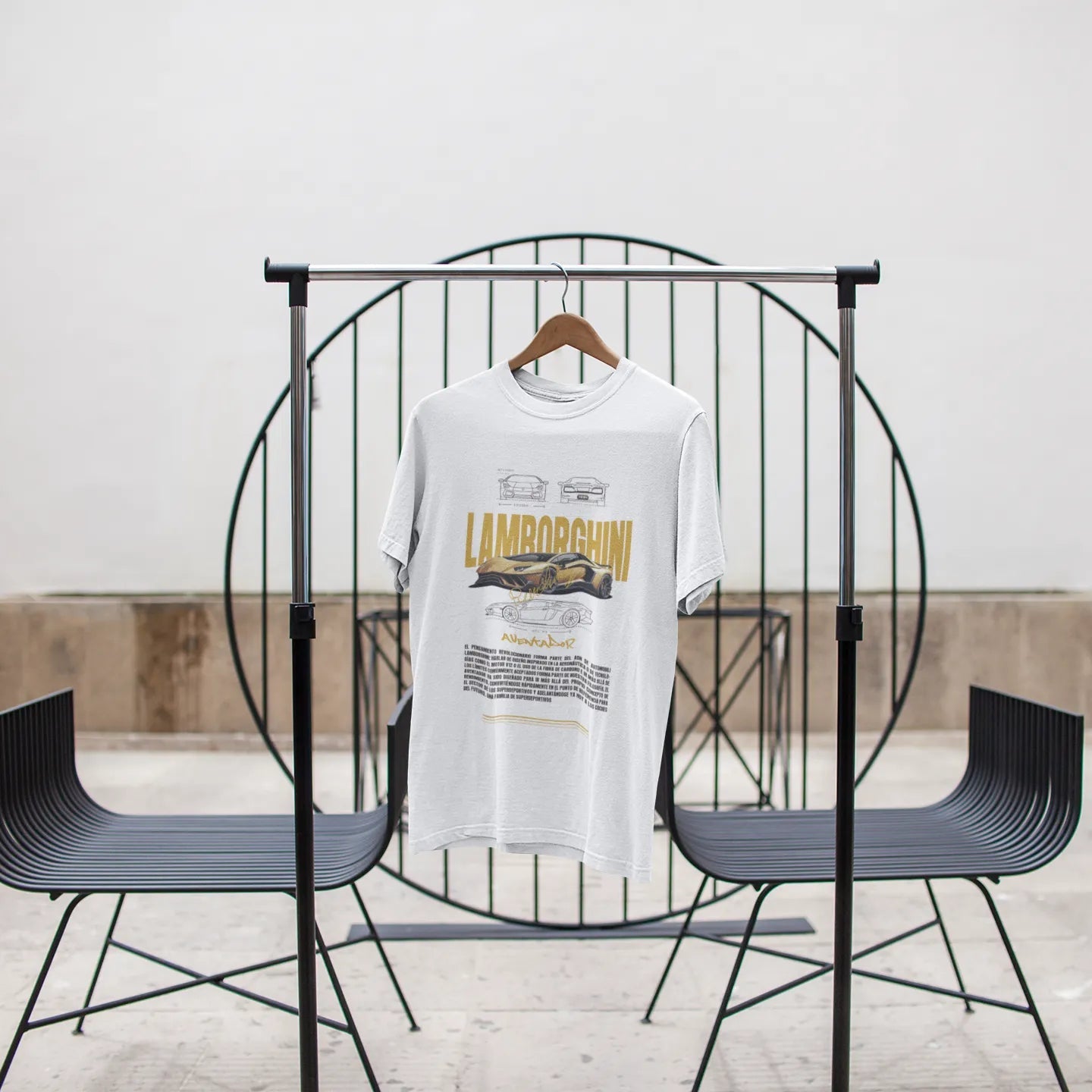 White t-shirt with text and graphics on a black chair against a white wall.