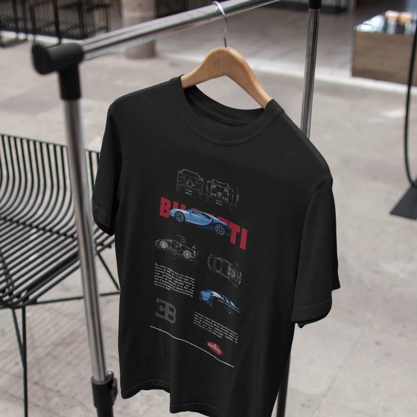 Black t-shirt with graphic design on a hanger against a blurred indoor background