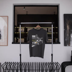 Black t-shirt with graphic design hanging on a rack in a modern interior setting.