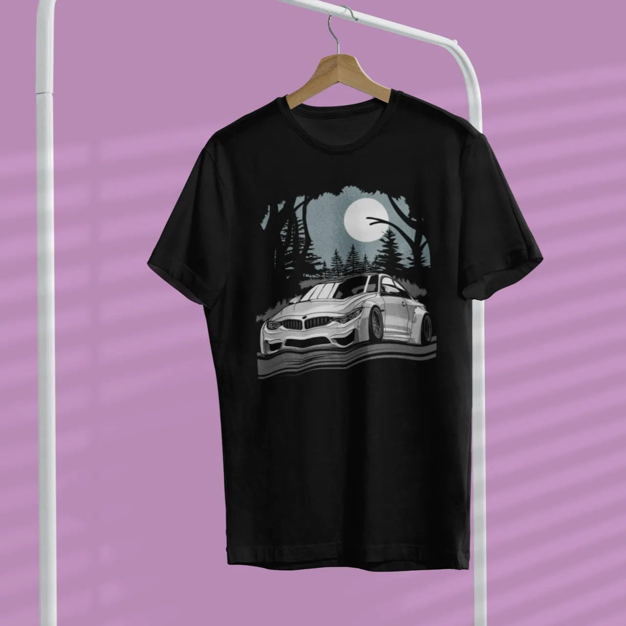 Black t-shirt with car graphic on a hanger against a purple background