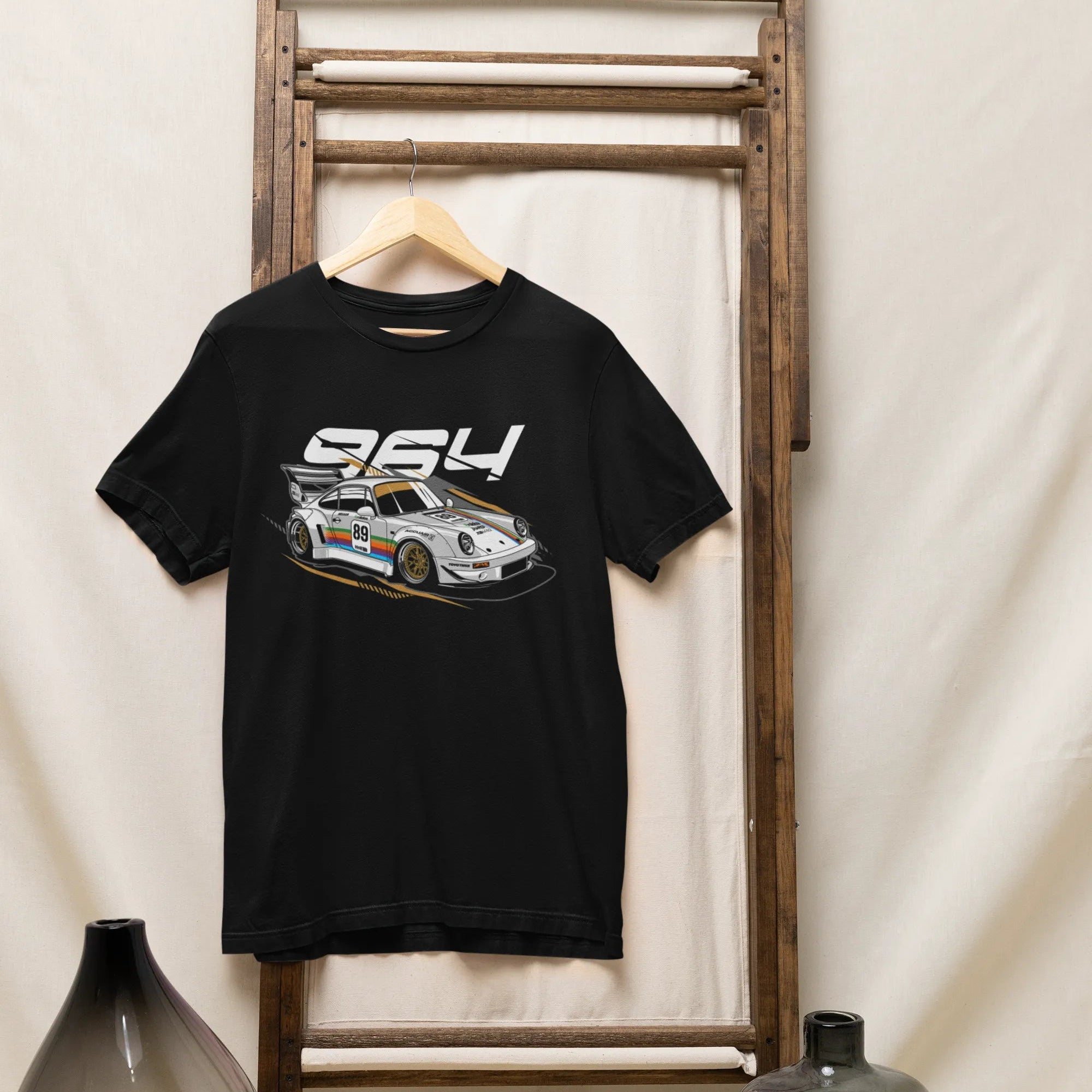 Black t-shirt with car graphic and '954' text on a wooden rack against a white wall.