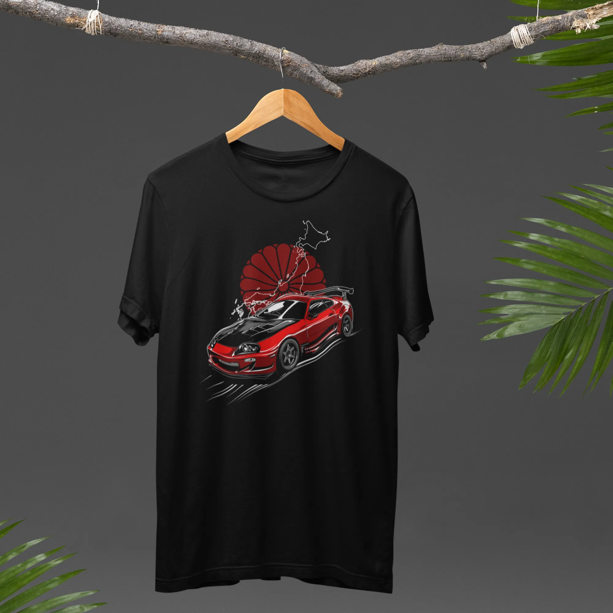 Black t-shirt with a red car graphic on a hanger against a dark background with green leaves.