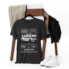 Black t-shirt with Chevrolet Camaro design on a chair with jeans and sneakers.