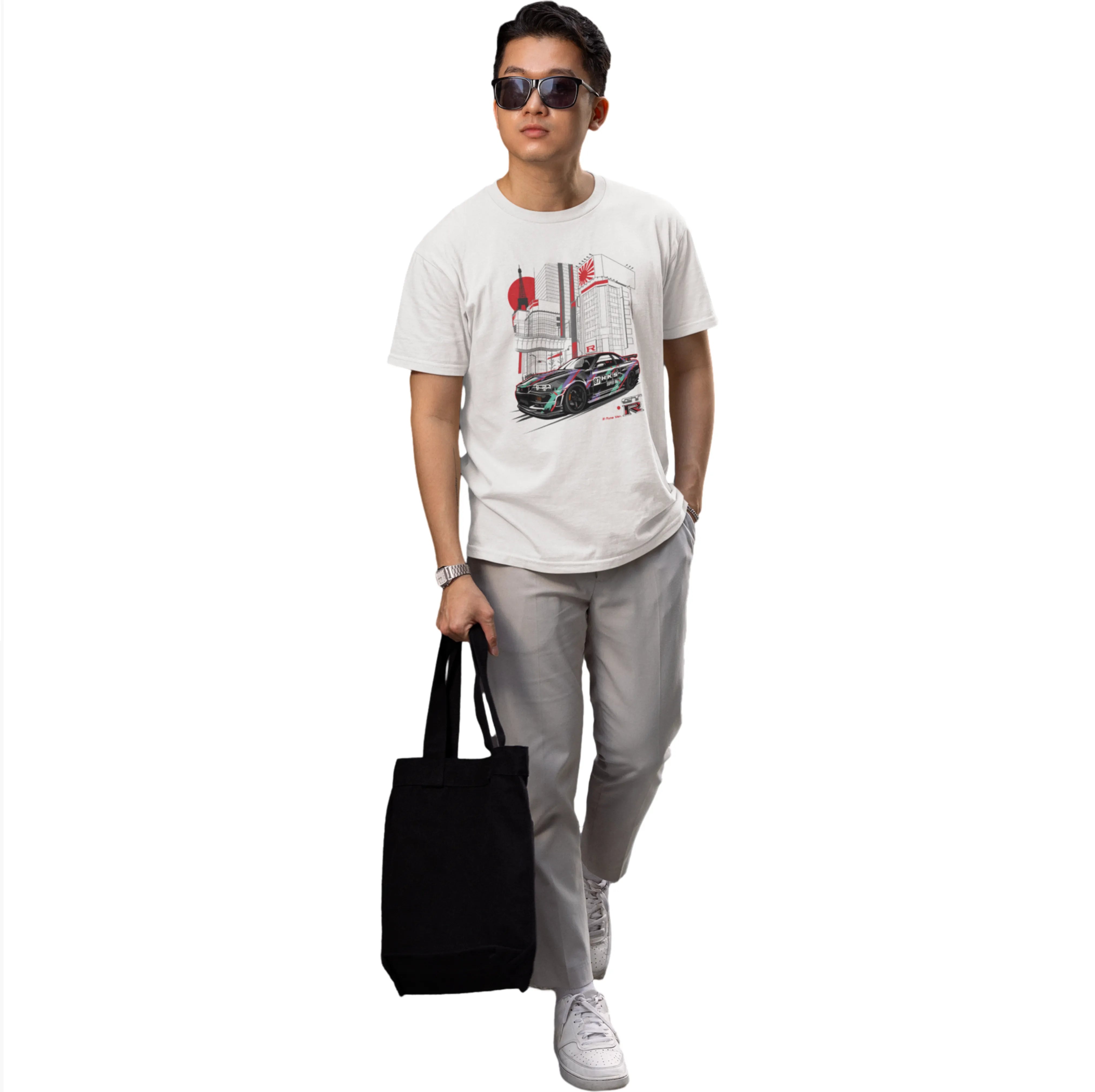 Person wearing a white t-shirt with a graphic design, holding a black bag on a white background
