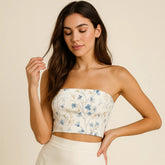 Woman wearing a floral strapless top and beige skirt against a beige background