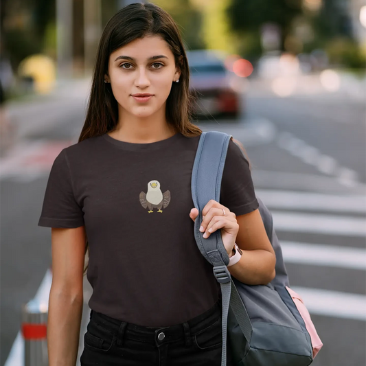 Woman wearing a black t-shirt with a graphic design, holding an apple, and carrying a gray backpack on a street.