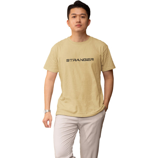 Person wearing a beige t-shirt with 'STRANGER' printed on it against a white background