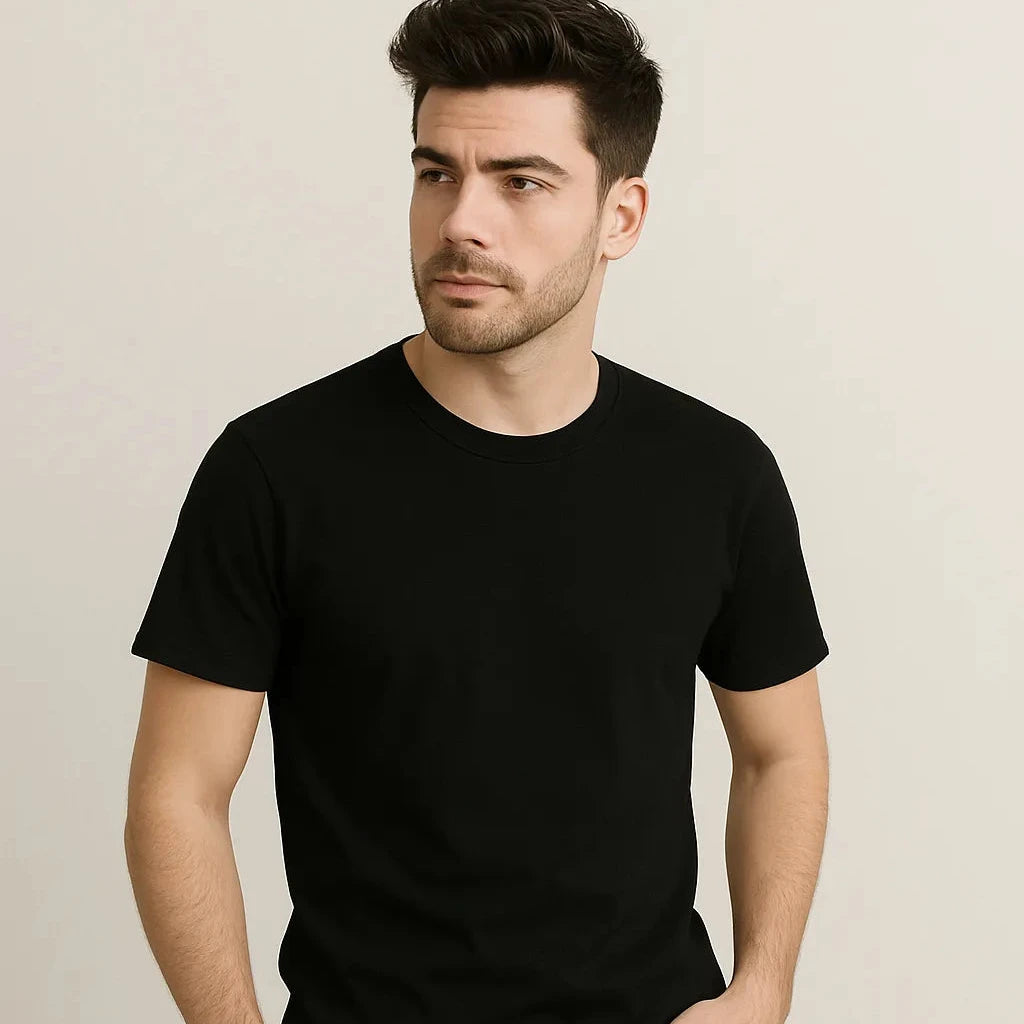 Man wearing a black t-shirt and dark jeans against a plain background