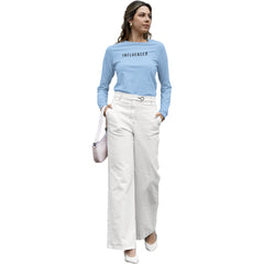Woman wearing a light blue 'INFLUENCER' shirt and white pants on a white background