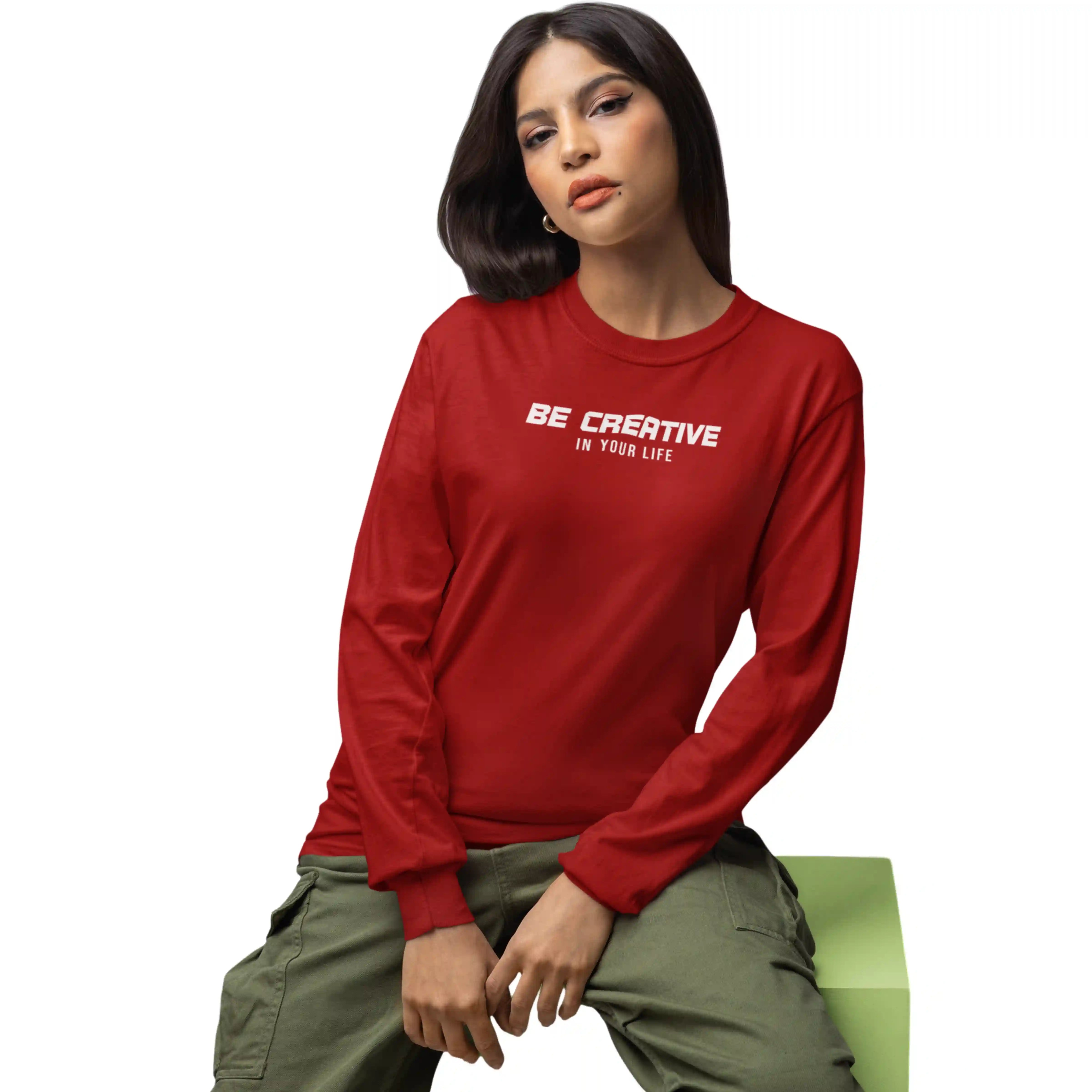 Person wearing a red sweatshirt with 'Be Creative In Your Life' text, sitting on a green bench.