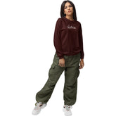 Woman wearing a burgundy sweatshirt and green cargo pants on a white background