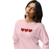 Woman wearing a pink sweatshirt with three red hearts on a white background