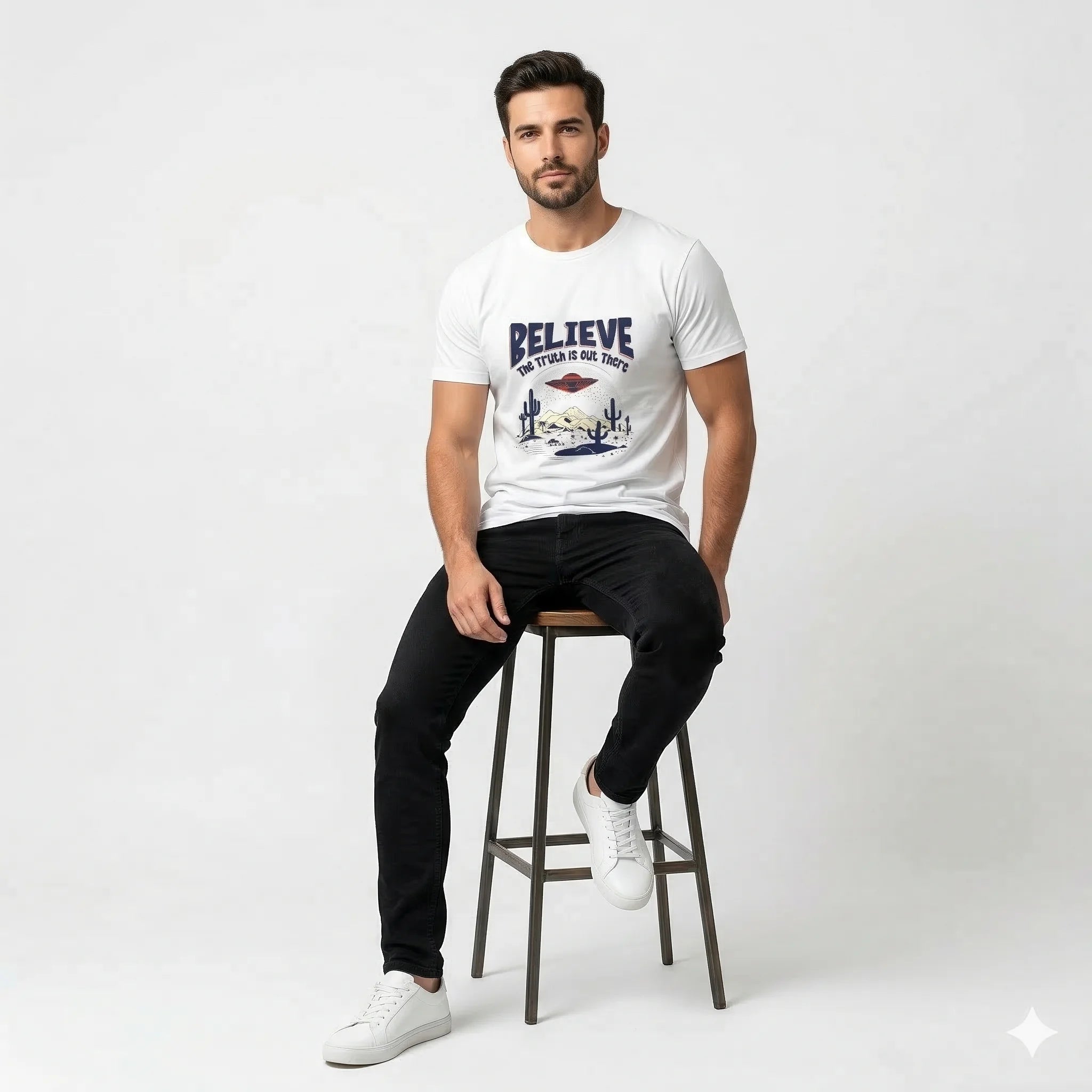 Man sitting on a stool wearing a white t-shirt with a graphic design and text.