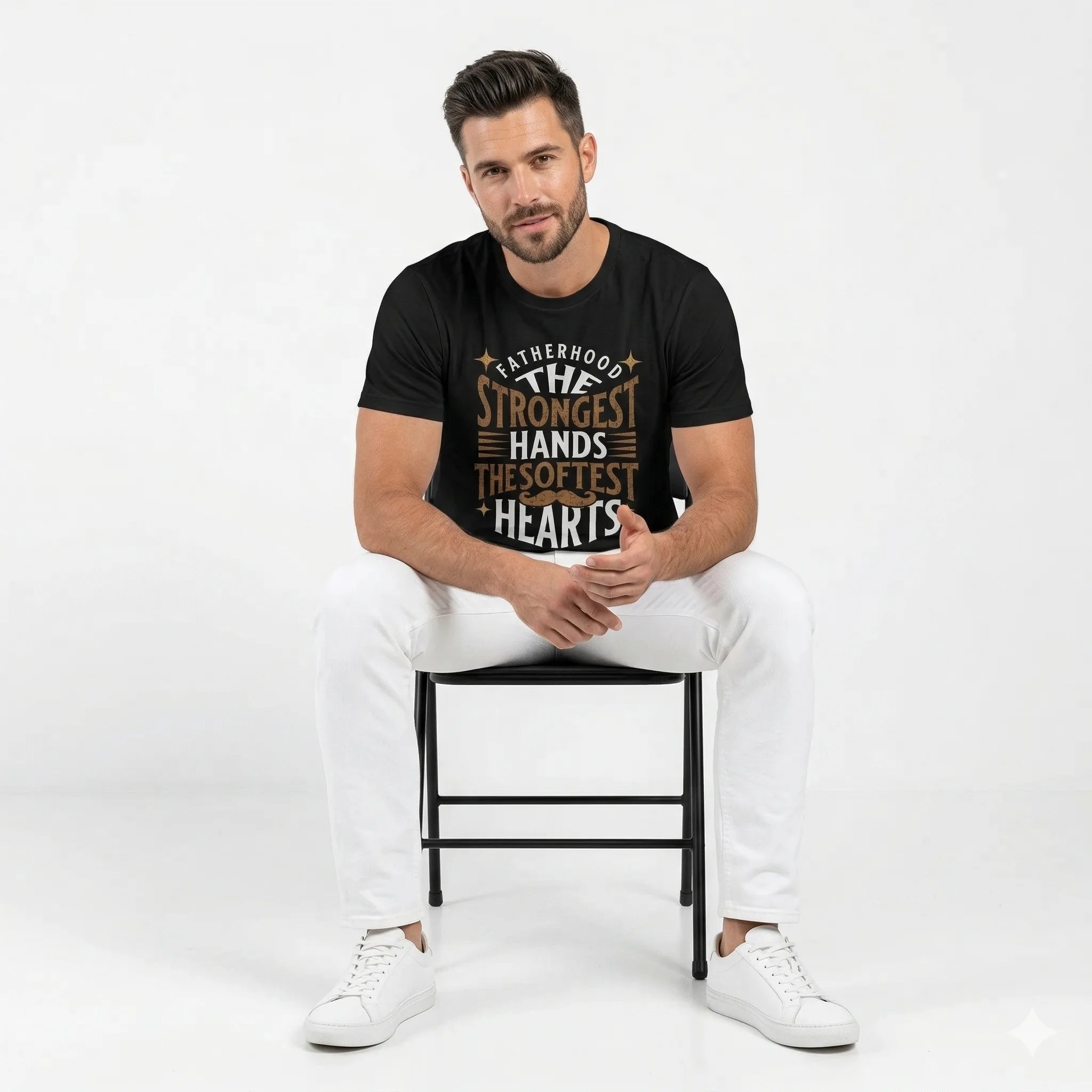 Man sitting on a chair wearing a black t-shirt with text, white pants, and white sneakers on a white background