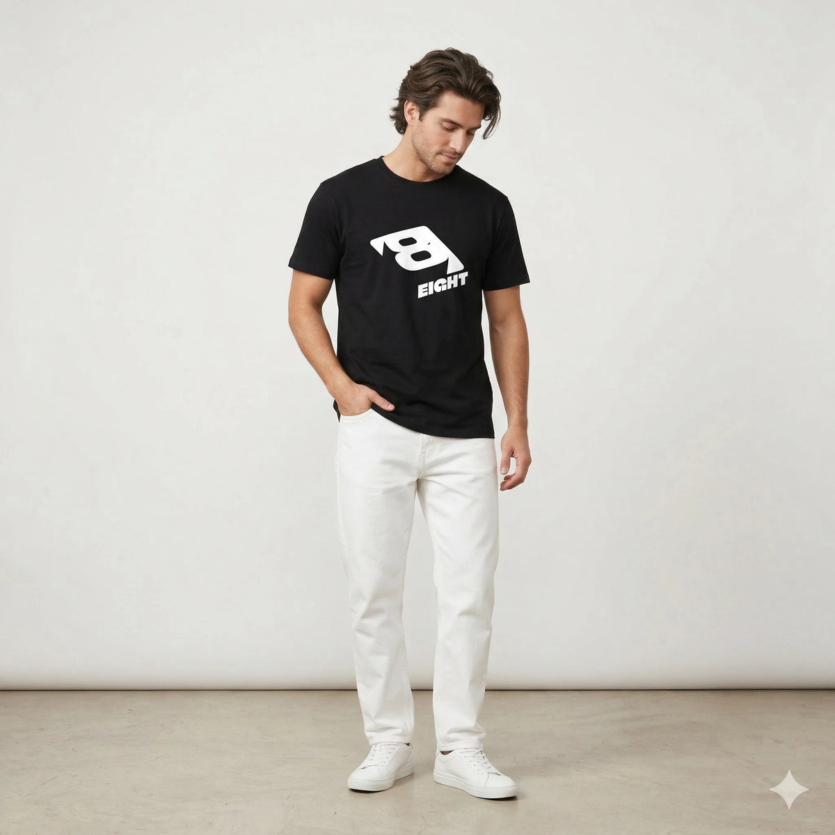 Black t-shirt with a white logo on a hanger against a white wall with plants.