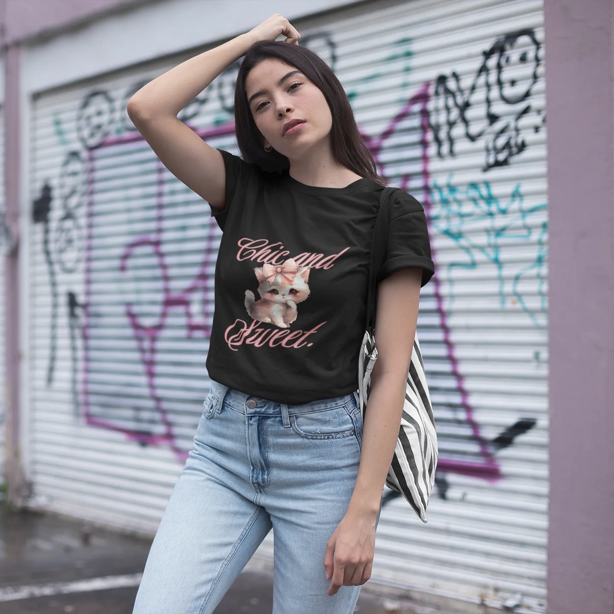 Woman wearing a black t-shirt with graphic design and text, standing in front of a graffiti-covered wall.